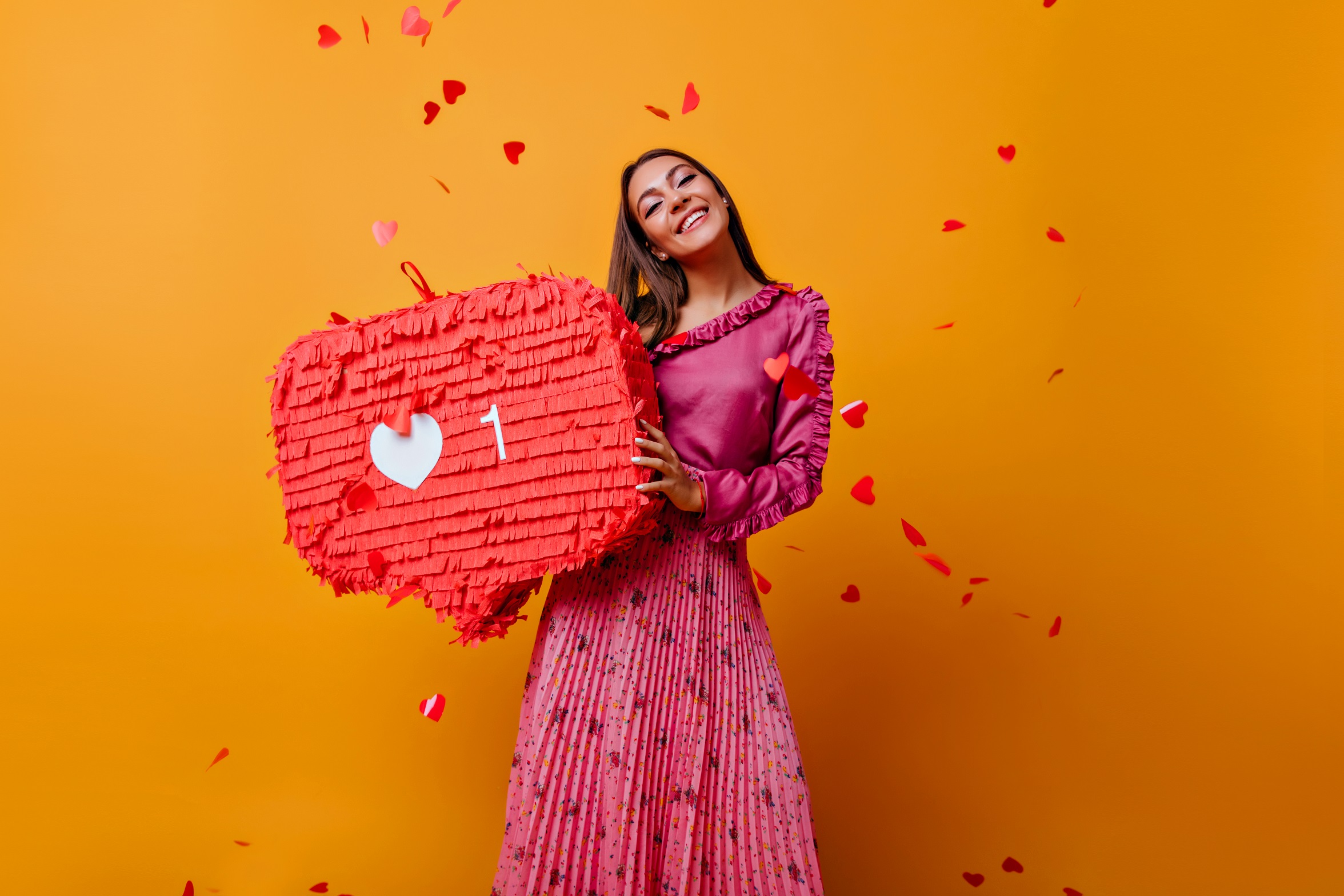 Satisfied woman in pink outfit laughing in studio. Adorable caucasian girl in long skirt standing on yellow background.